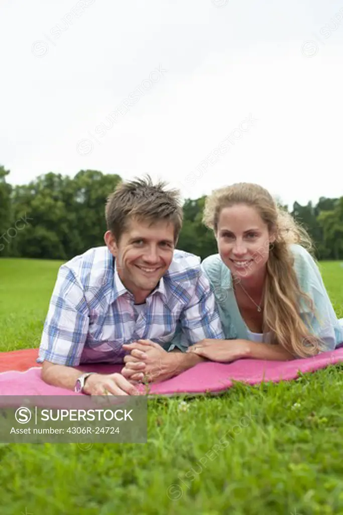 Mid adult couple lying on blanket and looking at camera