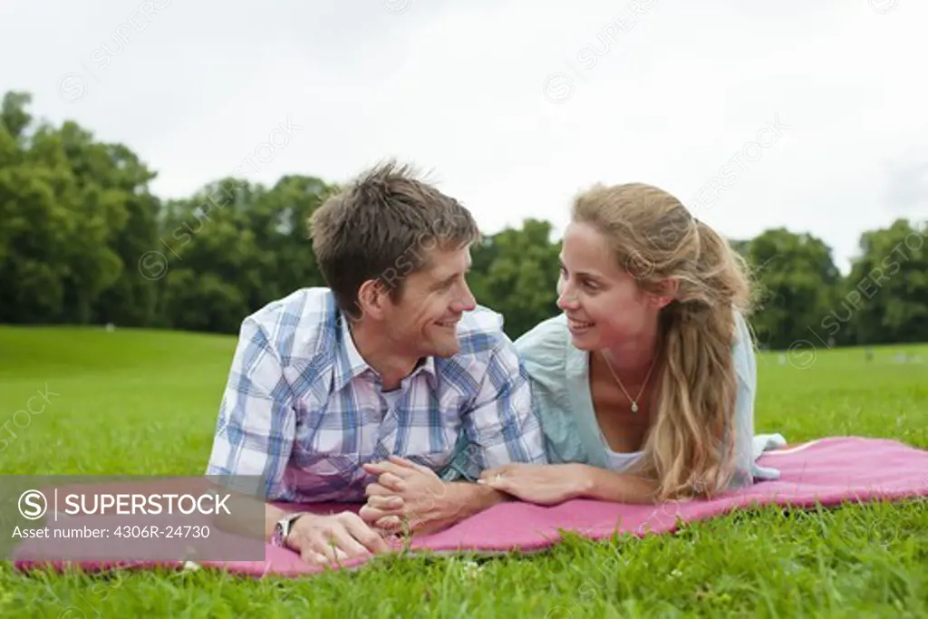 Mid adult couple lying on blanket and looking each other