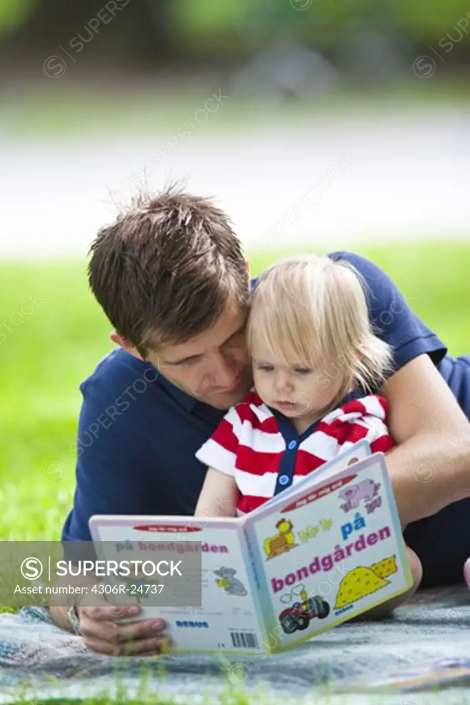 Mid adult father embracing daughter and reading her book