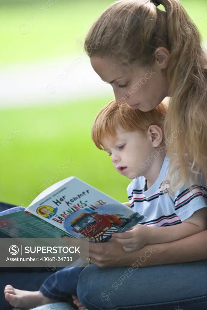 Mid adult women reading book for son