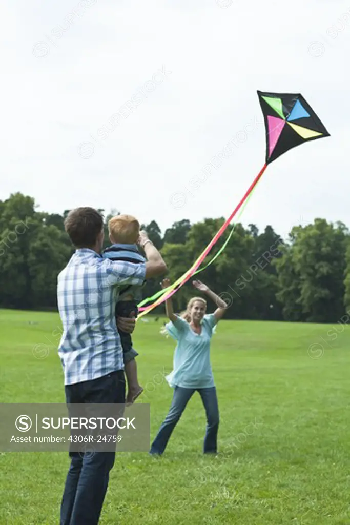 Parents and son playing with kite in park