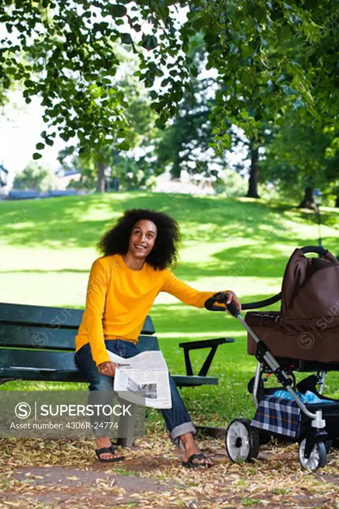 Smiling young man with baby carriage sitting on bench