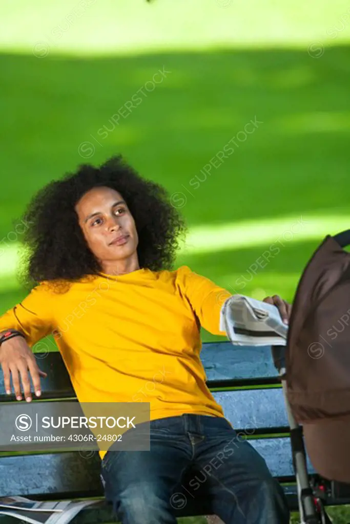 Young man with baby carriage sitting on bench