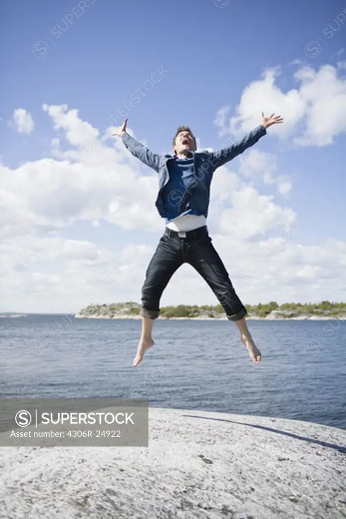 Mid adult man jumping on coastline