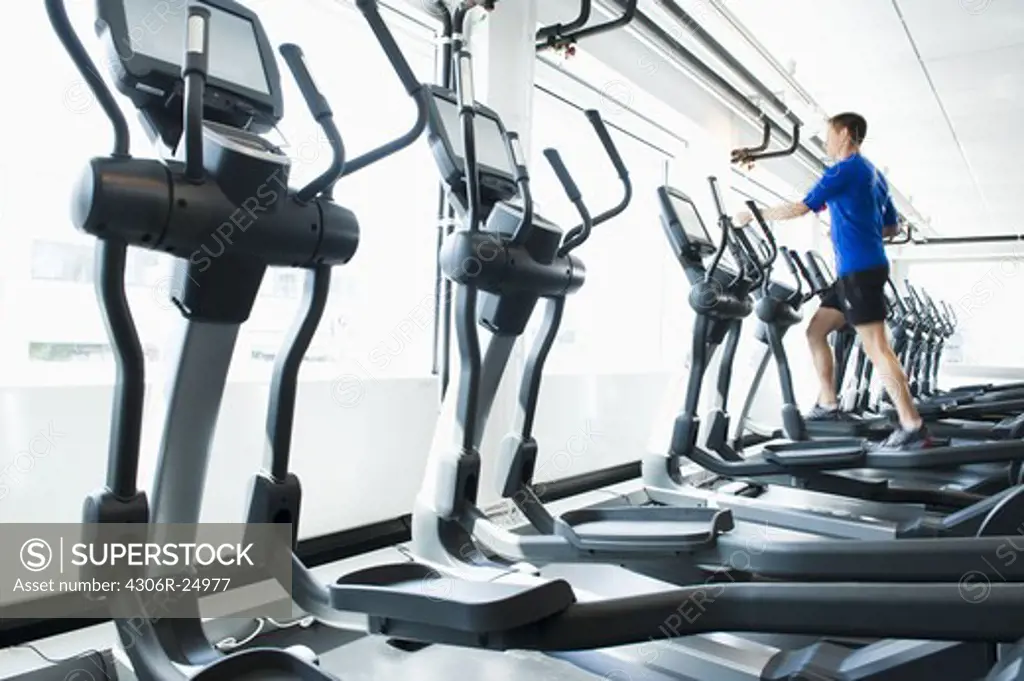 Man running on exercise machine in gym