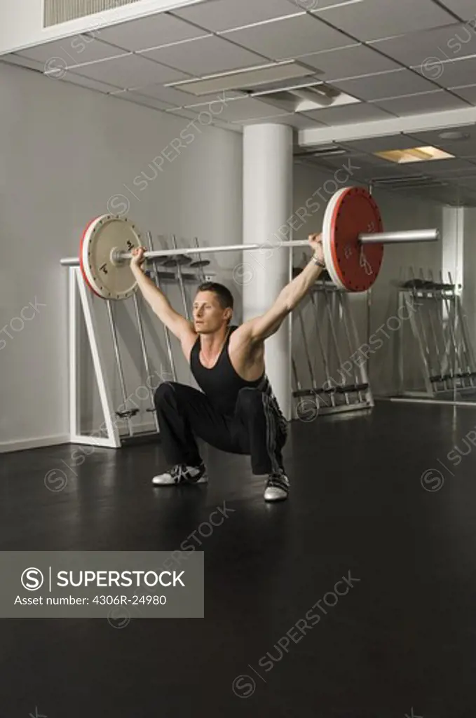 Male athlete lifting barbell in gym