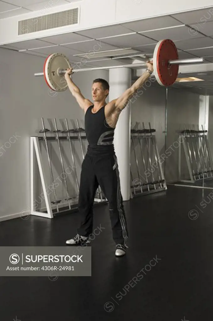 Male athlete lifting barbell in gym