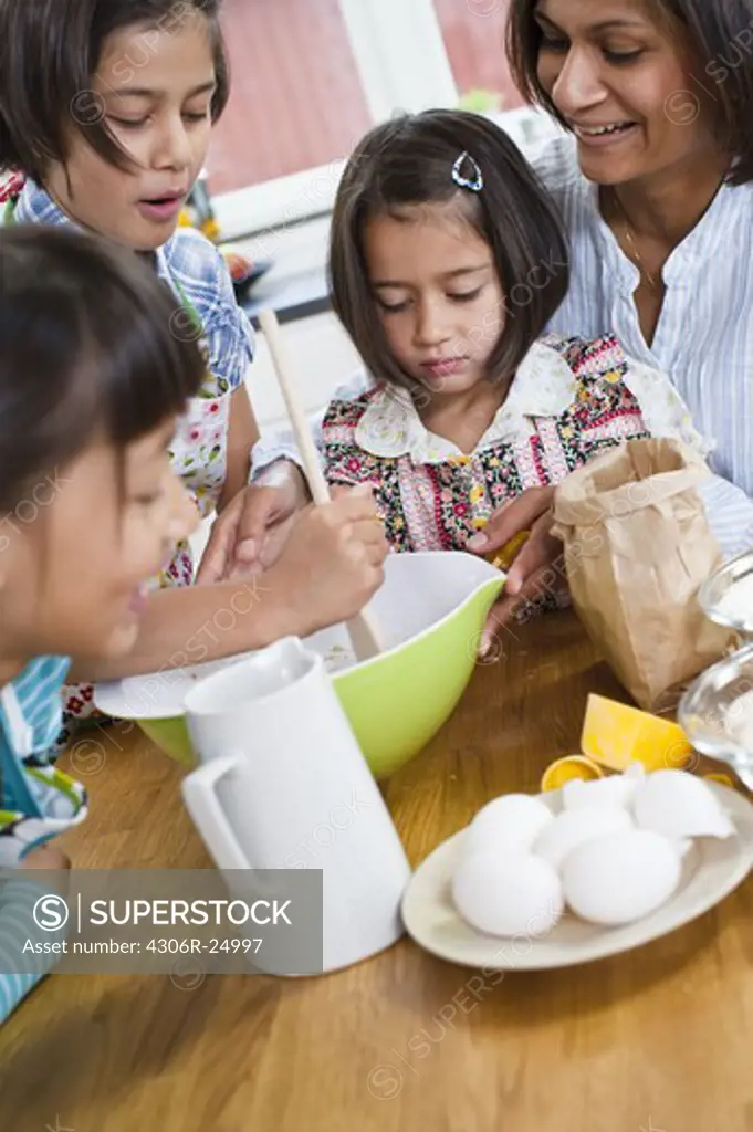 Mother baking with girls in kitchen