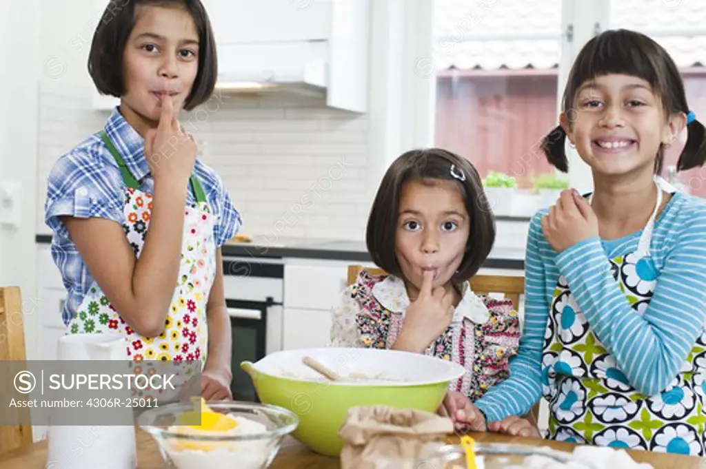 Portrait of three girls baking in kitchen