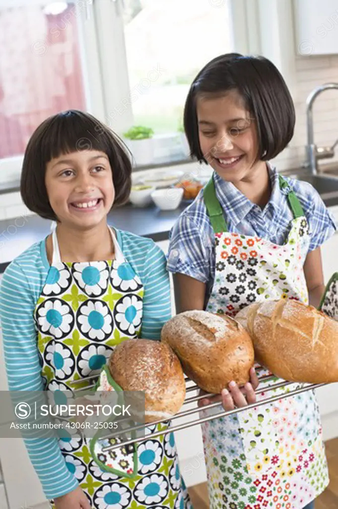 Two girls holding fresh bread in kitchen