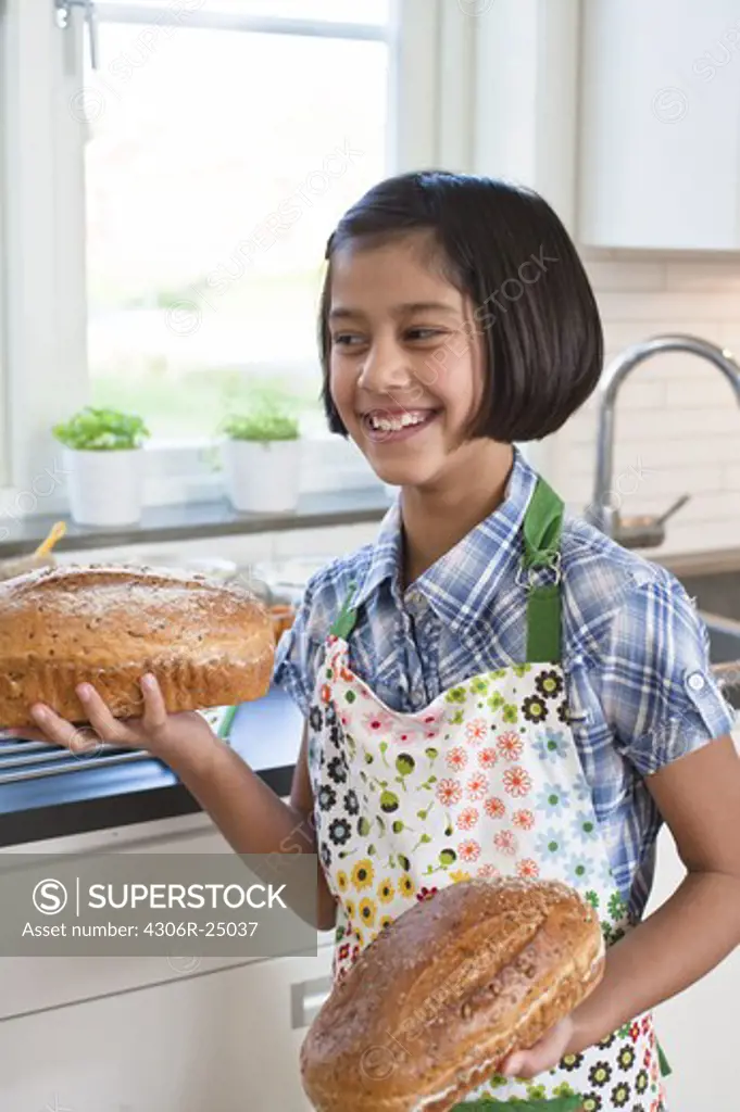 Girl holding loafs of bread and smiling