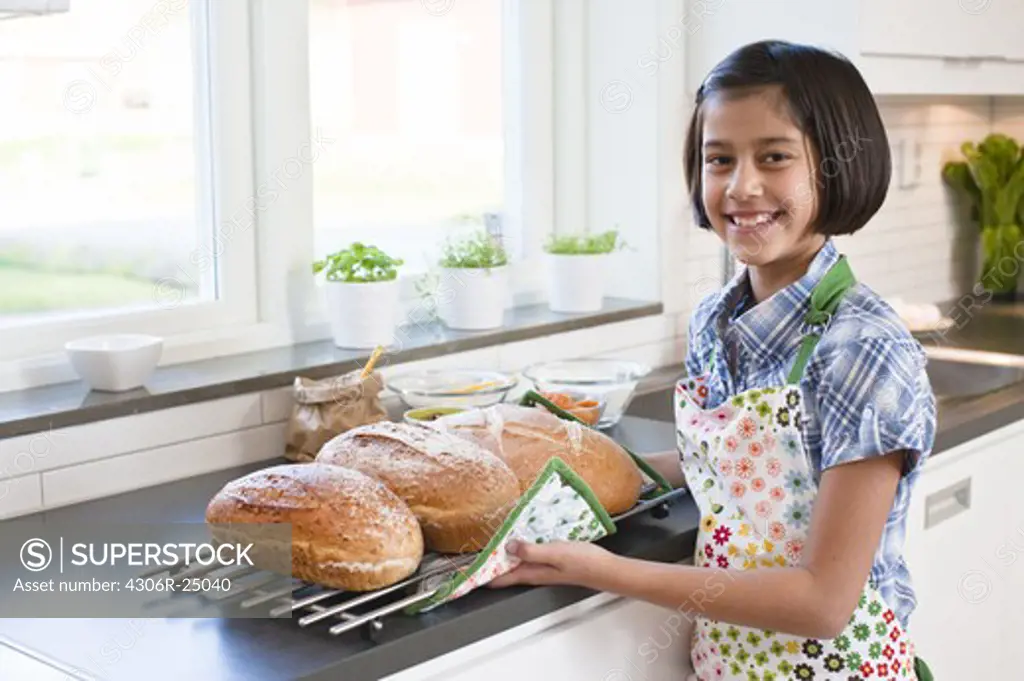 Girl holding metal grate with hot bread loafs