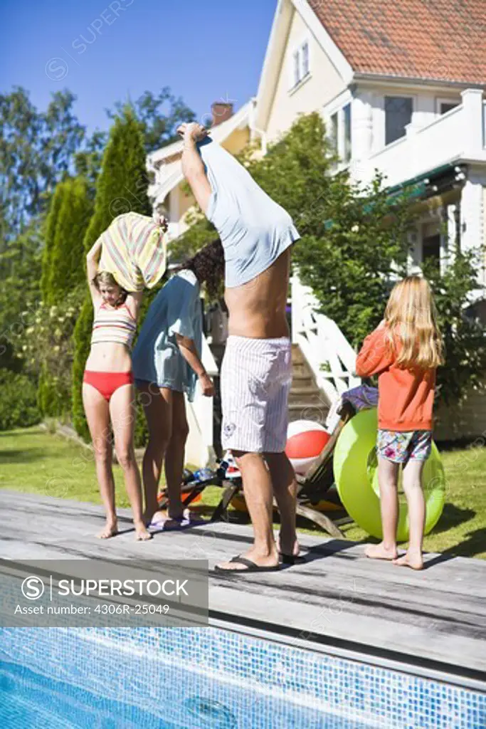Family taking off cloths near swimming pool