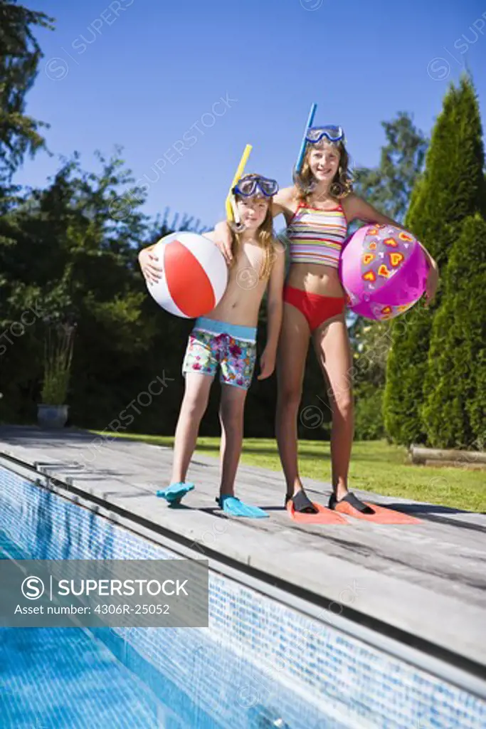 Sisters in scuba masks and flippers near swimming pool