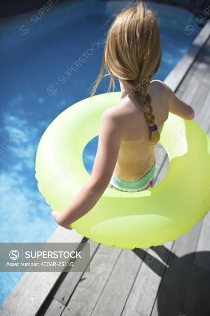 Daughter holding inflatable ring on  the edge of swimming pool