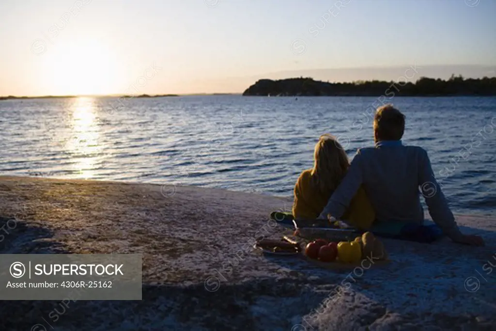 Couple relaxing by sea at sunset