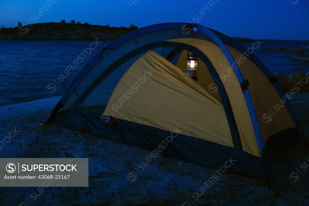 Illuminated tent by sea at dusk