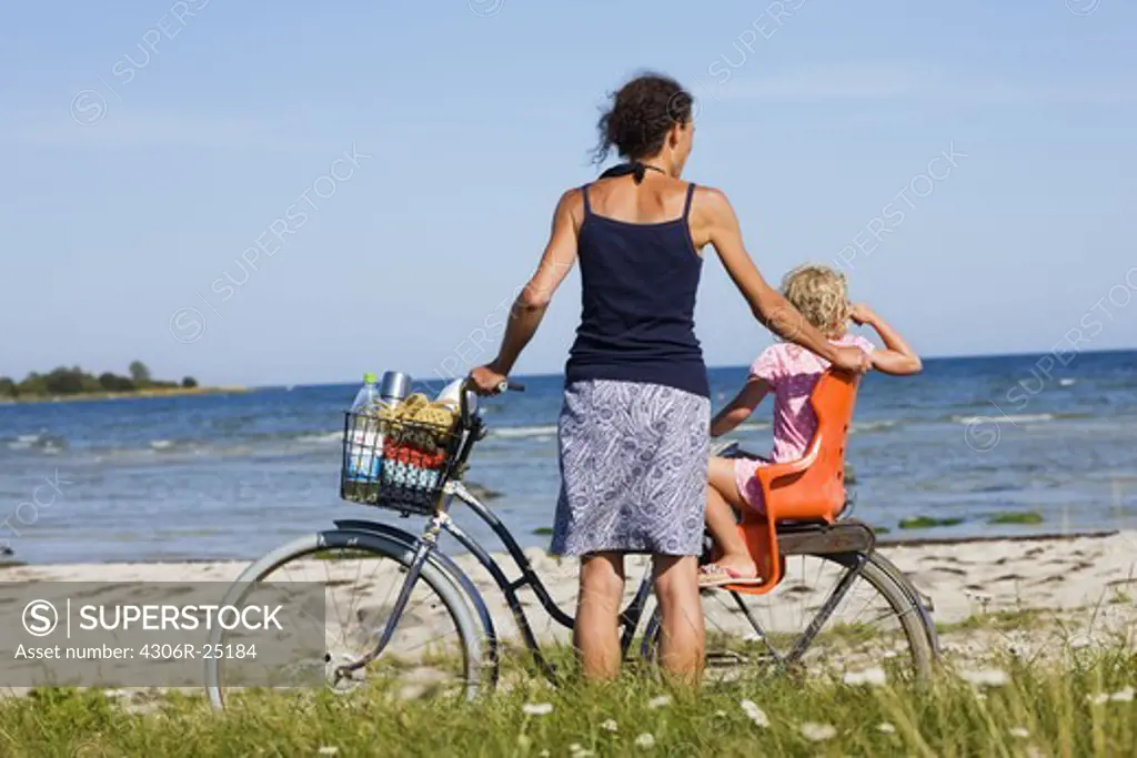 Mother and daughter with bicycle on beach
