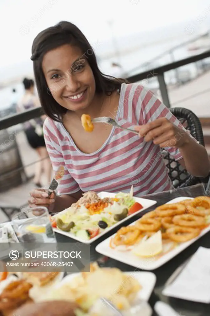 Portrait of woman eating meal at outdoor restaurant