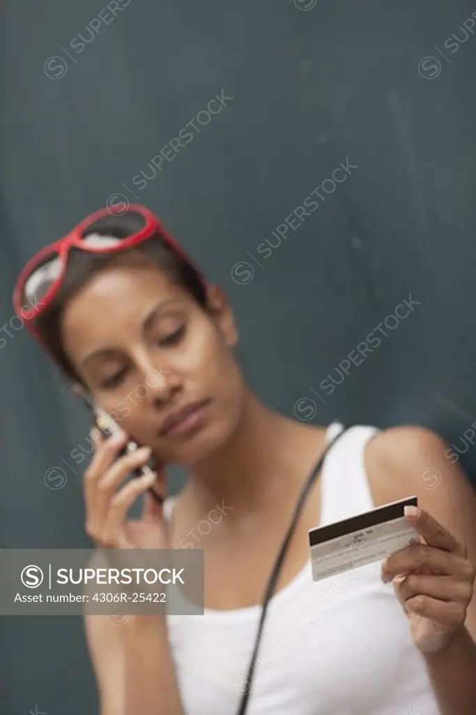 Woman using mobile phone holding credit card