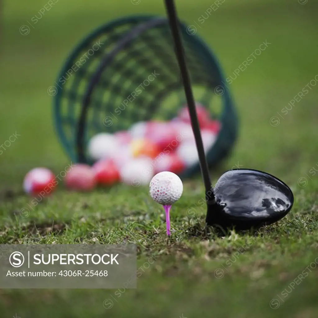 Golf ball on tee beside golf club