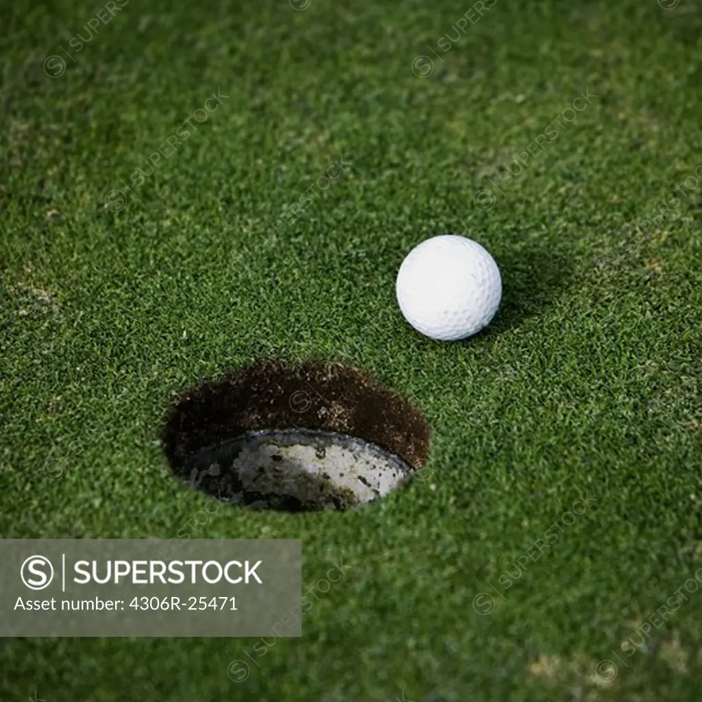 Golf ball beside hole