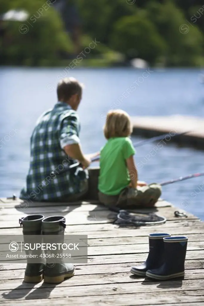 Father with son fishing, rubber boots on foreground