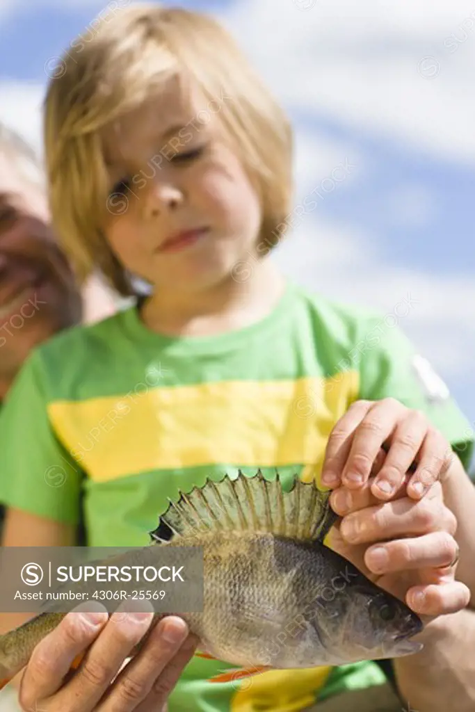 Father and son holding fish, focus on foreground