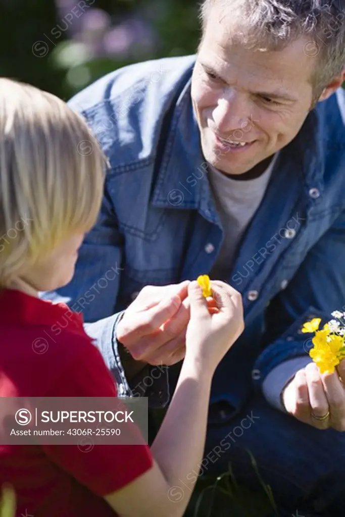 Father and son with flowers in bright sunlight