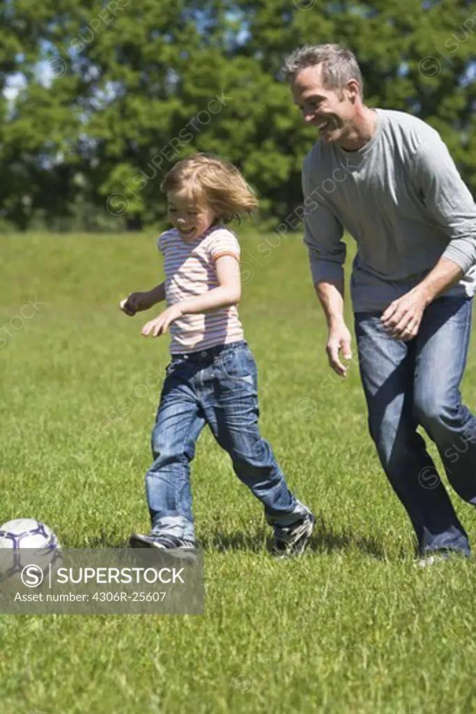 Father and son playing football in bright sunlight
