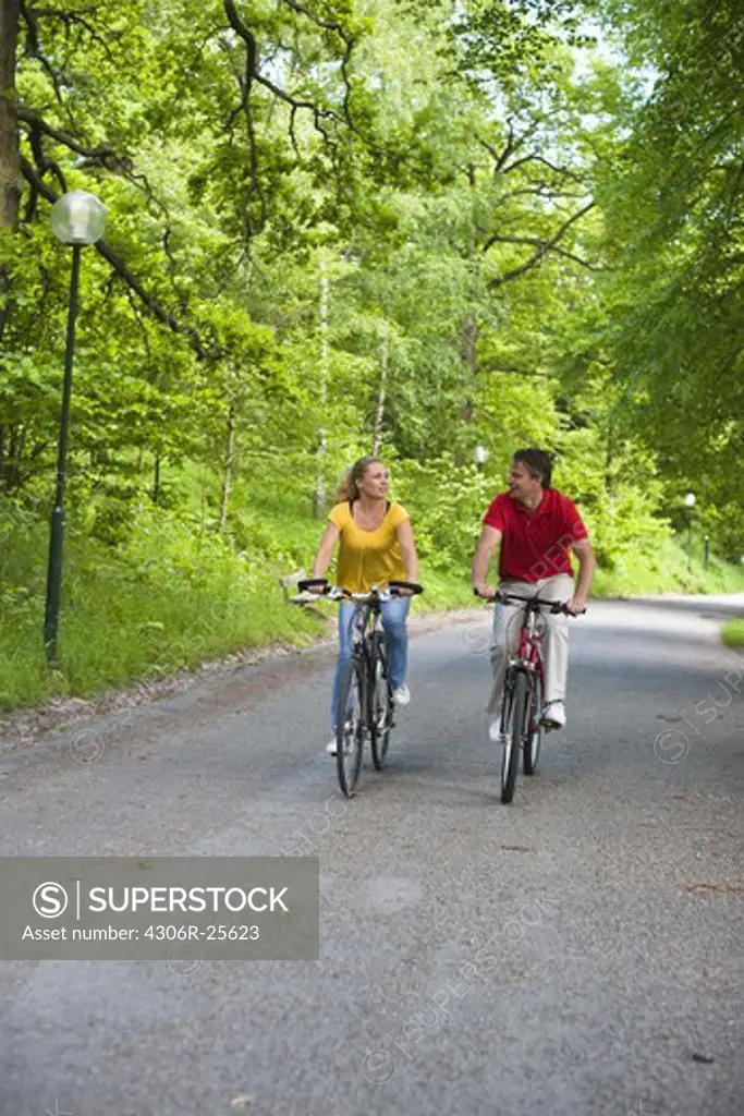 Young couple riding bikes in park