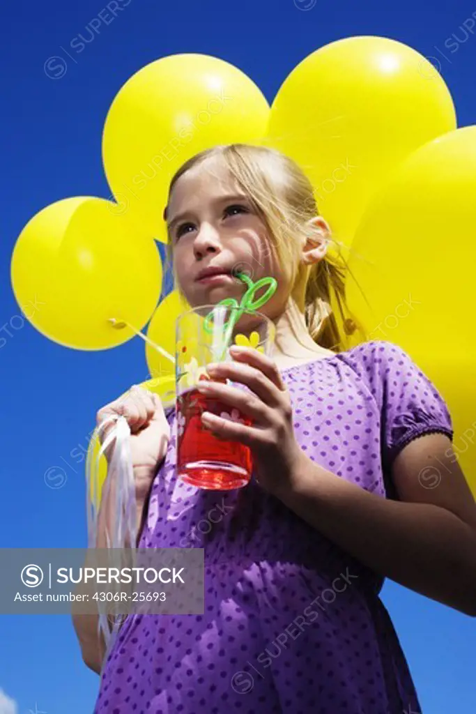 Low angle view of girl holding bunch of balloons