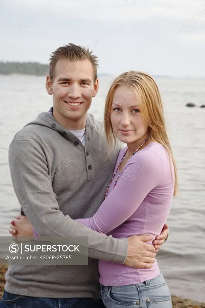 Portrait of young couple embracing by sea