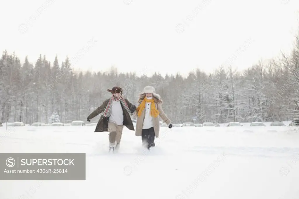 Mid adult couple holding hands and running