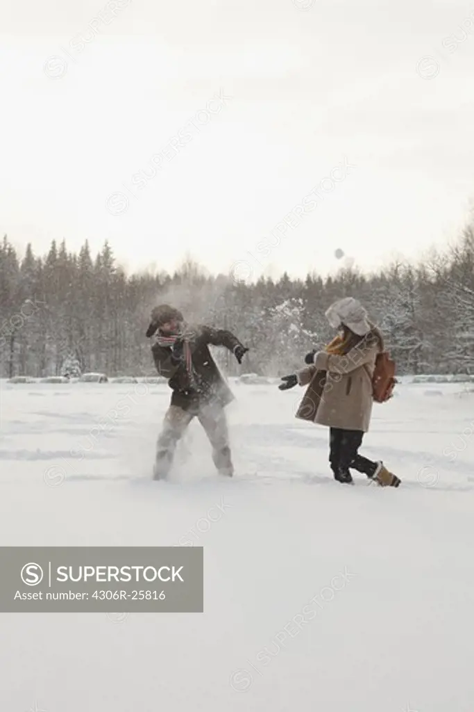 Mid adult couple holding playing with snowballs
