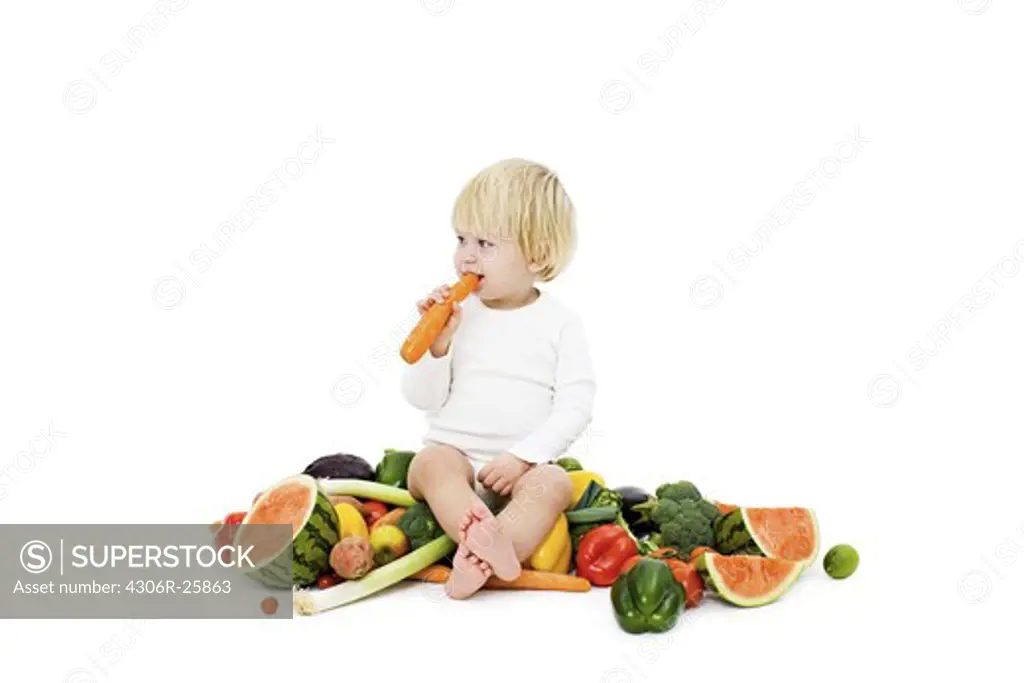 Studio shot of baby boy surrounded by fresh vegetables