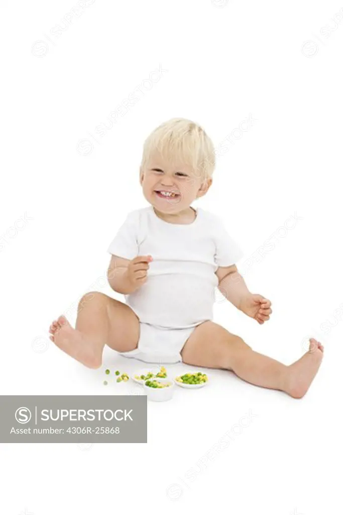 Studio shot of baby boy eating peas