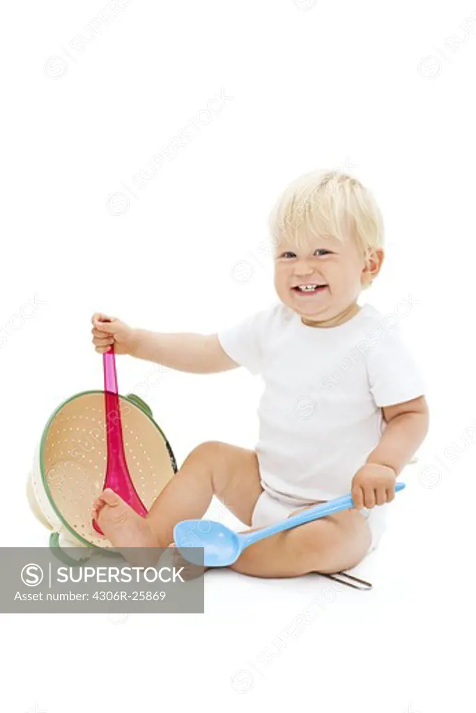Studio shot of baby boy playing with ladle