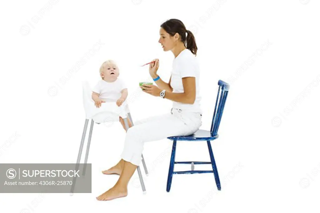 Boy in high chair being fed by mother