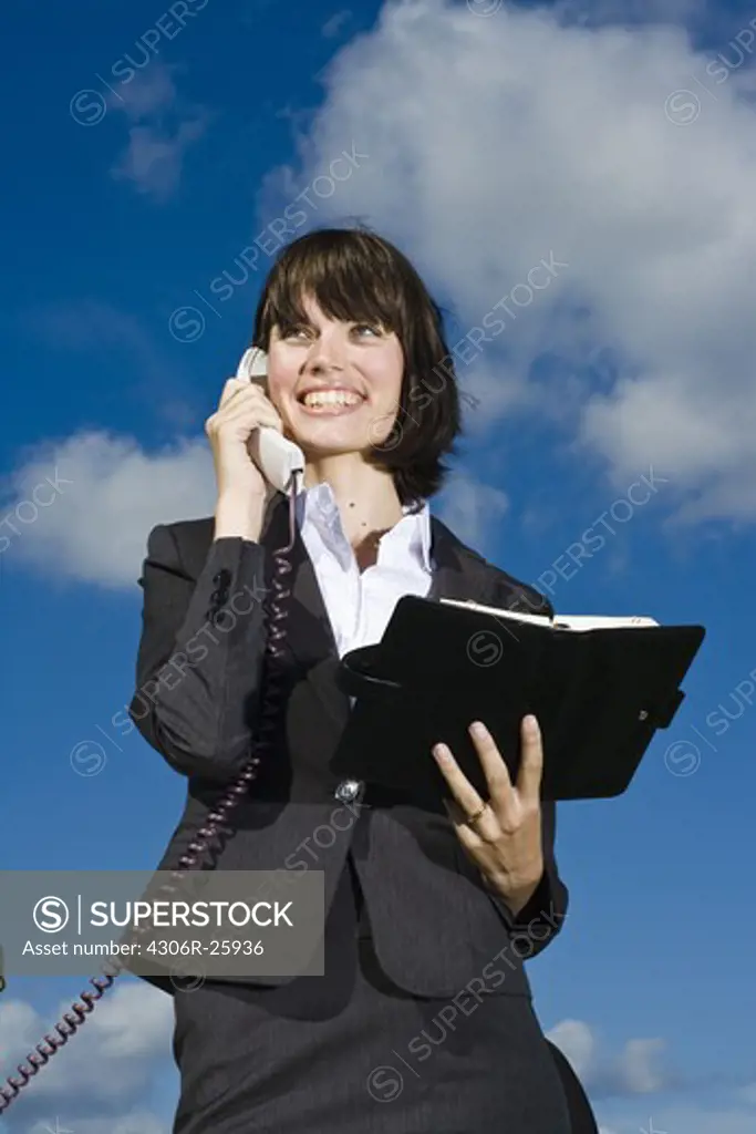 Portrait of businesswoman on the phone against blue sky