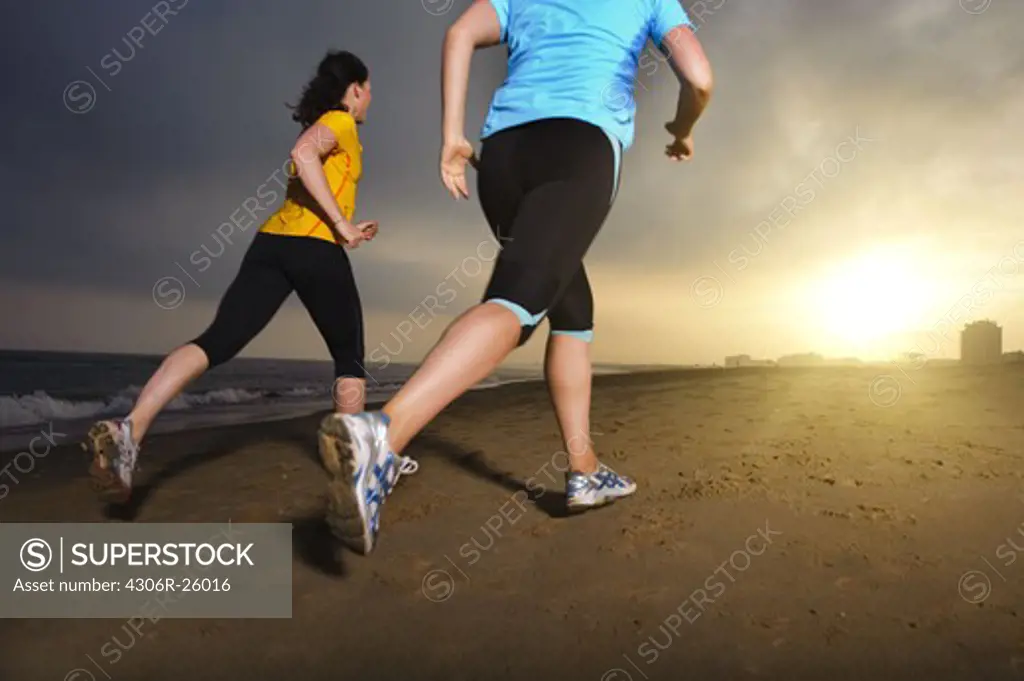 Women jogging on beach at dusk