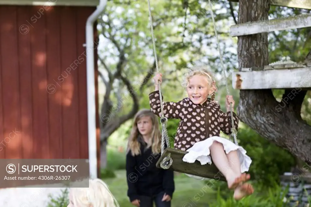 Girl playing on rope swing in garden