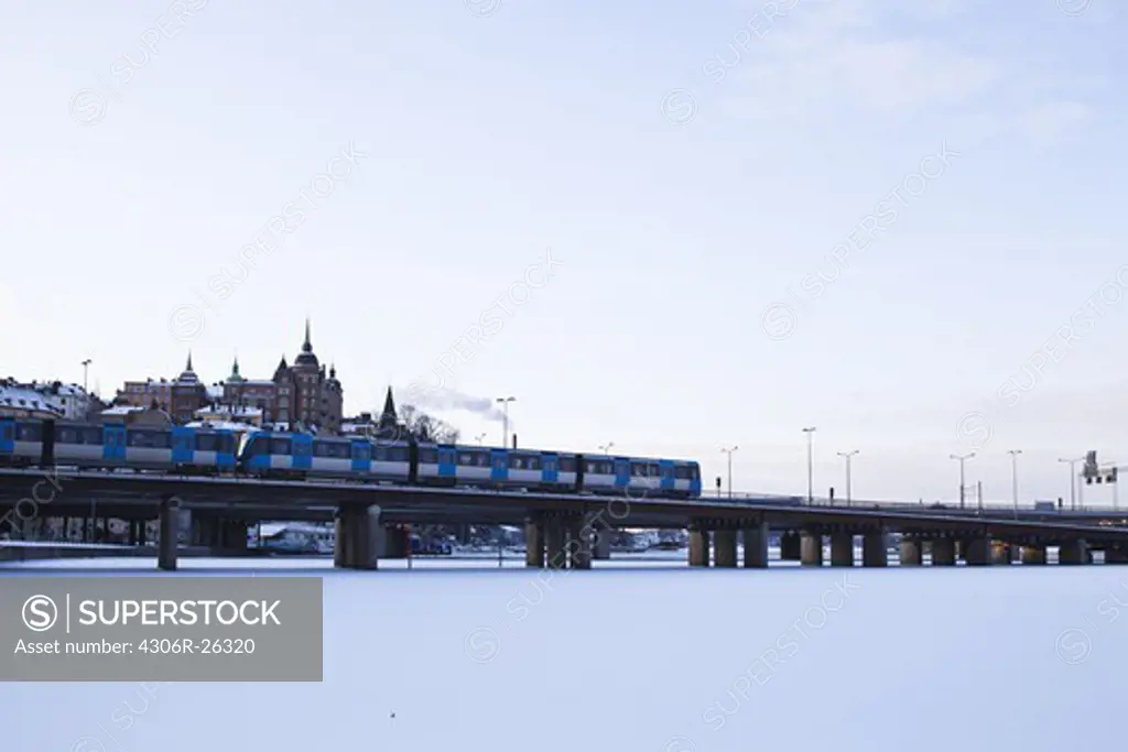 Passenger train passing through bridge over frozen lake