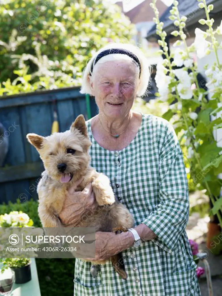 Portrait of senior woman holding dog in garden