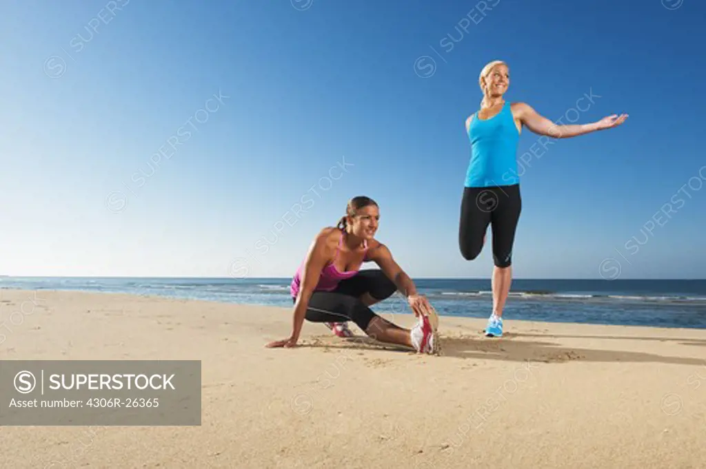 Two women exercising on beach