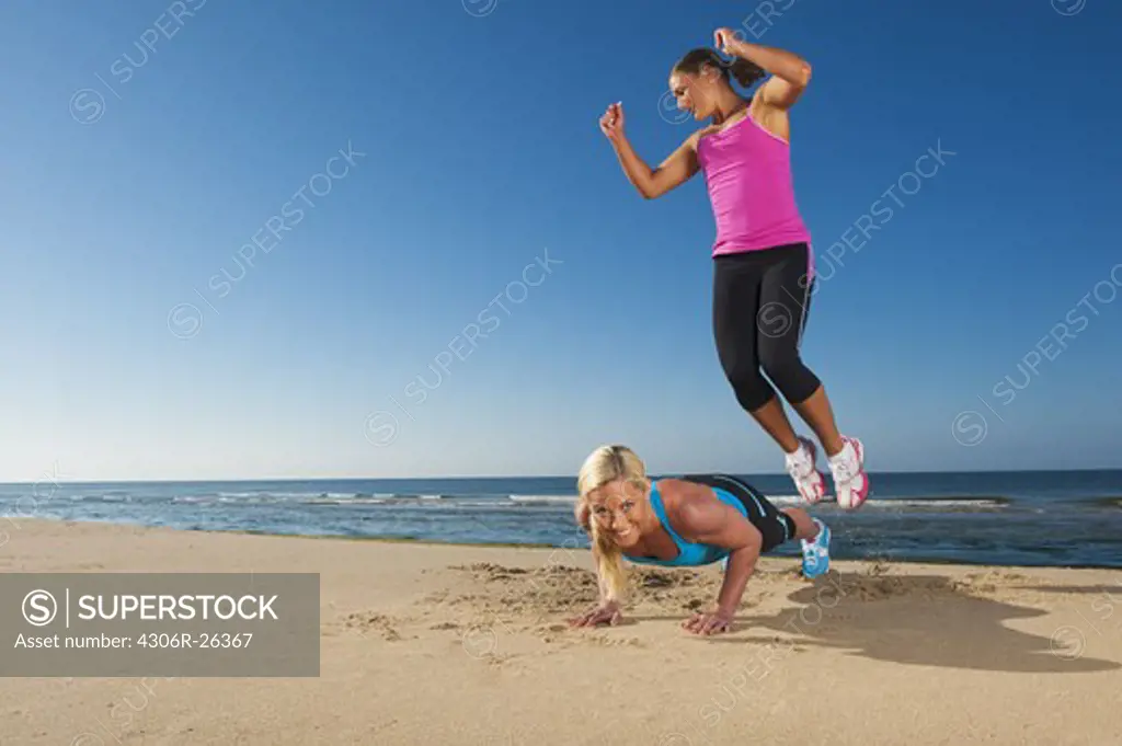 Two women exercising on beach