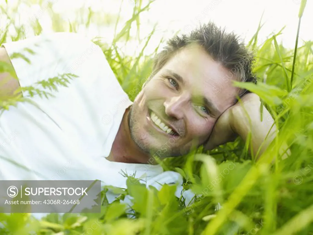 Ekero, Young man lying on grass, looking away and smiling