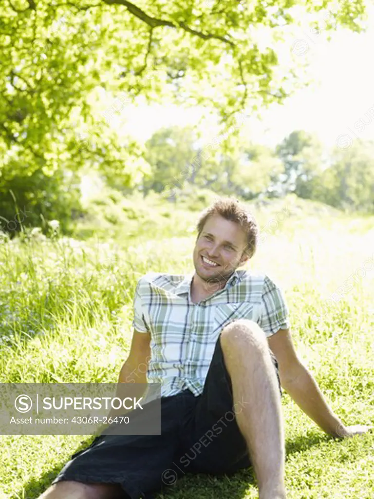 Yong man sitting on grass and smiling
