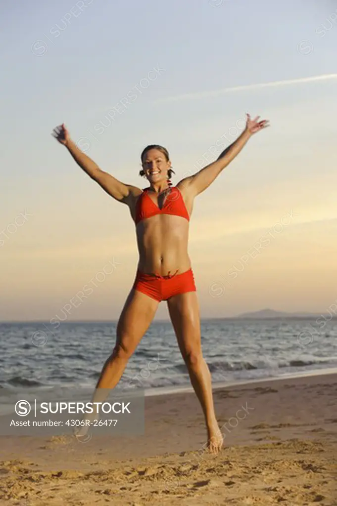 Young woman wearing bikini jumping on beach