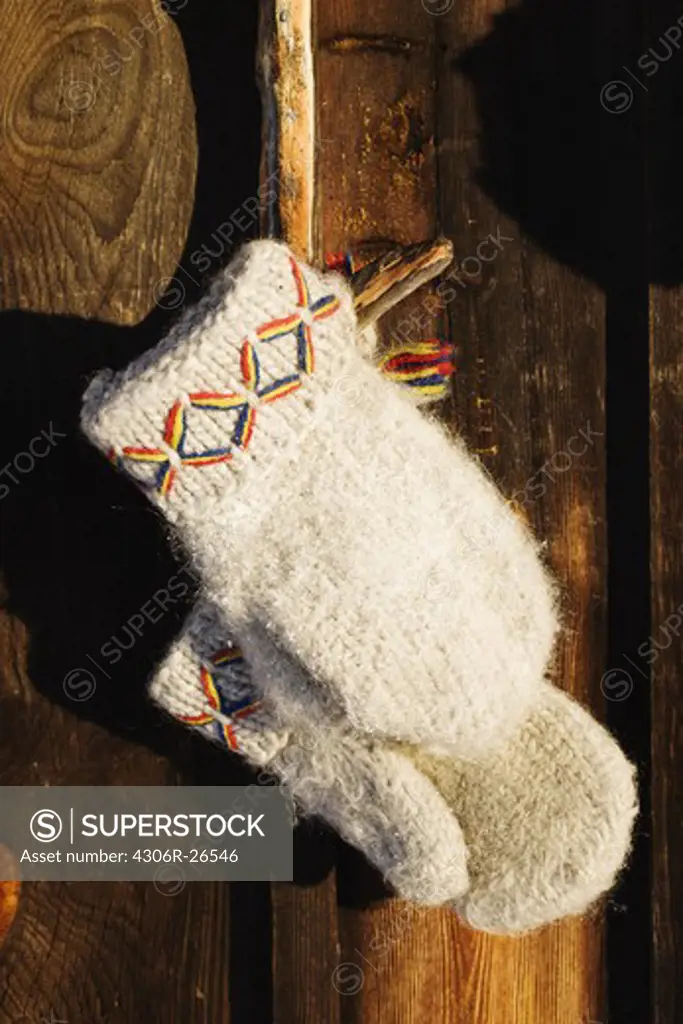 Traditional fingerless gloves hanging outside log cabin, close-up